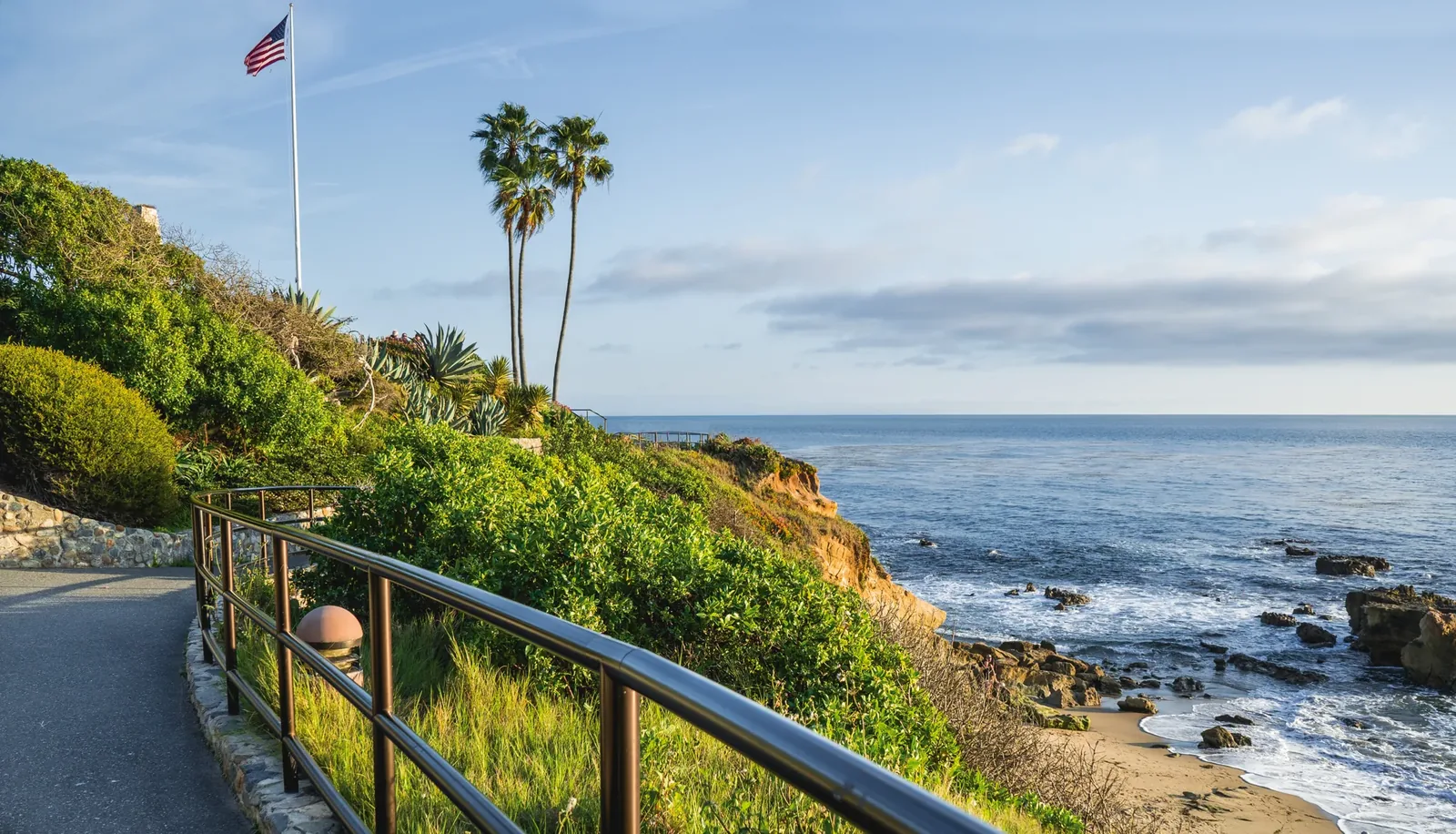 A coastal walking path with palm trees and the Pacific in Laguna Beach