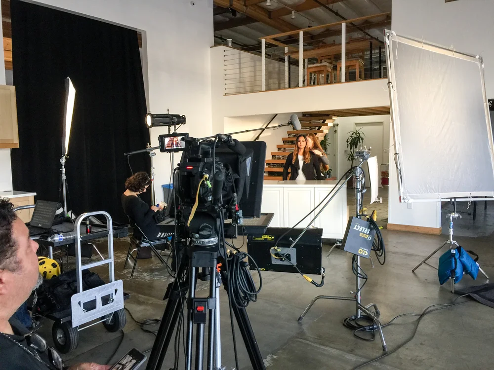 A presenter being prepared on set while the camera crew sets up the shot